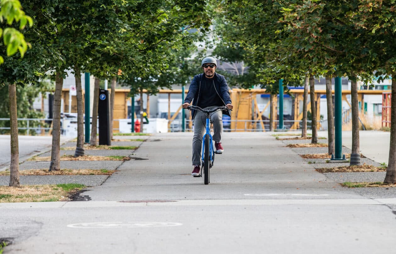 Someone riding Norco Scene VLT e-bike toward the camera in an urban park