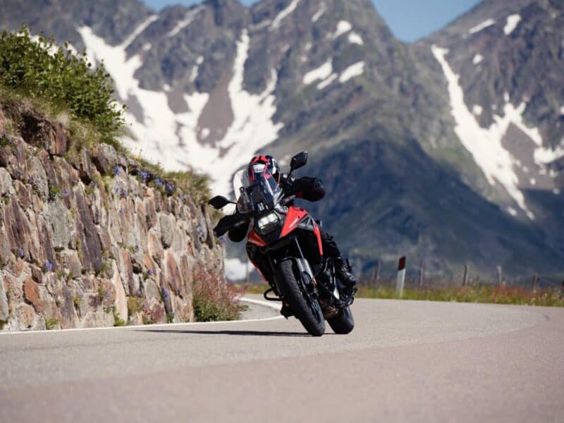 Suzuki V-Strom 1050 leaning into a corner with snow caped mountains in the background