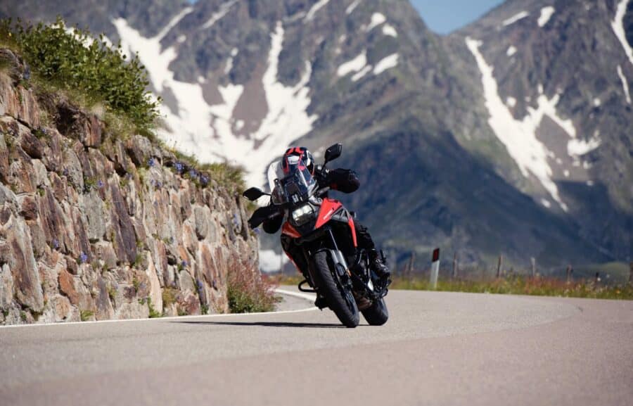 Suzuki V-Strom 1050 leaning into a corner with snow caped mountains in the background