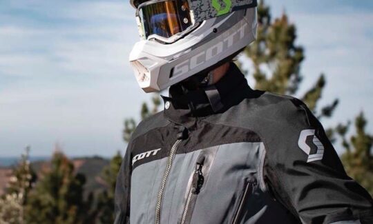 A man standing in a motorcycle jacket wearing a dual sport helmet