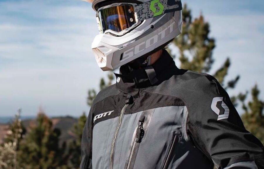 A man standing in a motorcycle jacket wearing a dual sport helmet