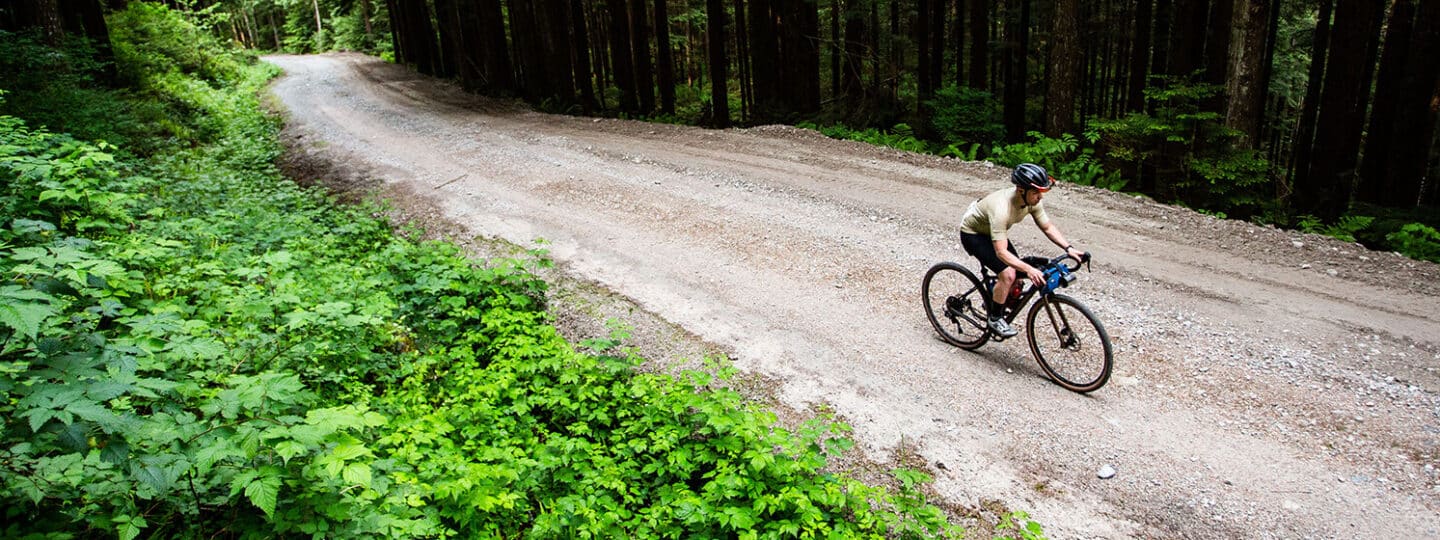 man riding a bike on a gravel road in the forest