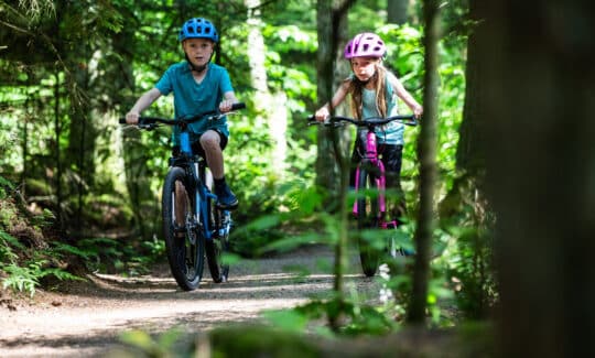 A boy and a girl riding bikes through the forest