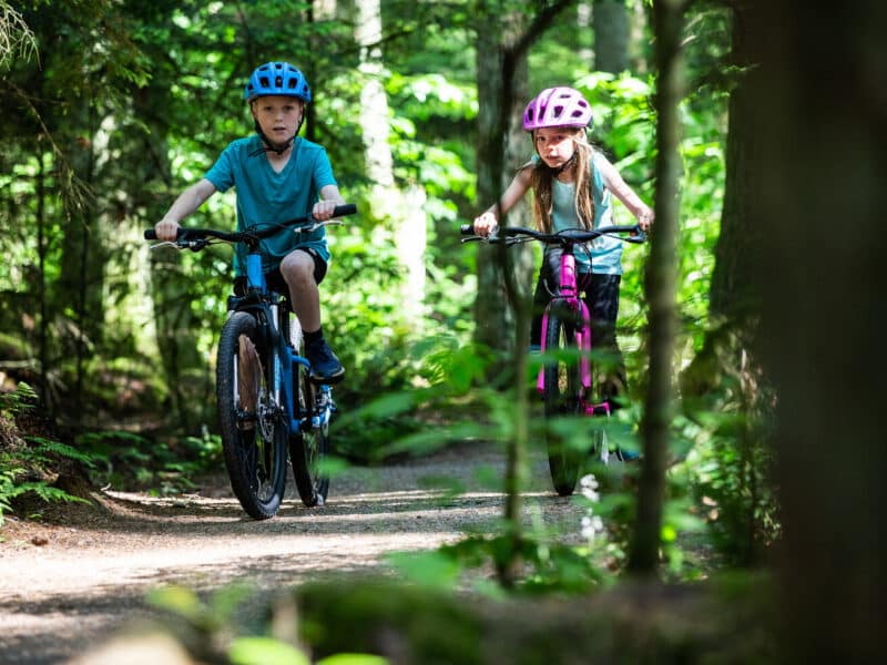 A boy and a girl riding bikes through the forest