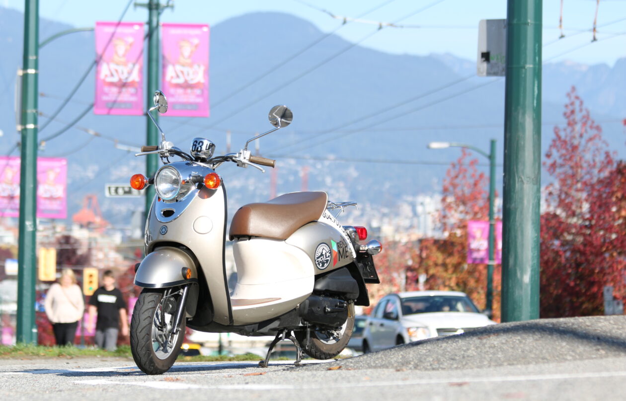 A Yamaha Vino scooter parked on the side of the road