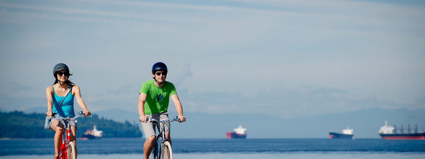 Two cyclist riding along an ocean pathway