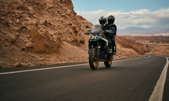 A BMW R 1300 GS with a rider and passenger in the desert.