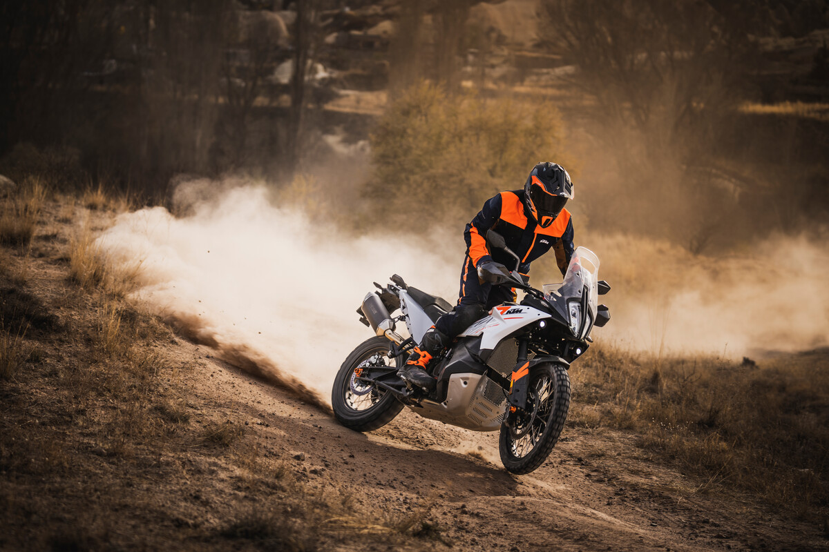 A rider on a KTM 790 ADV on a dirt road kicking up dust