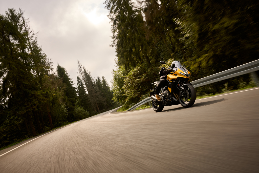 A rider going fast on a yellow Triumph Tigersport 800