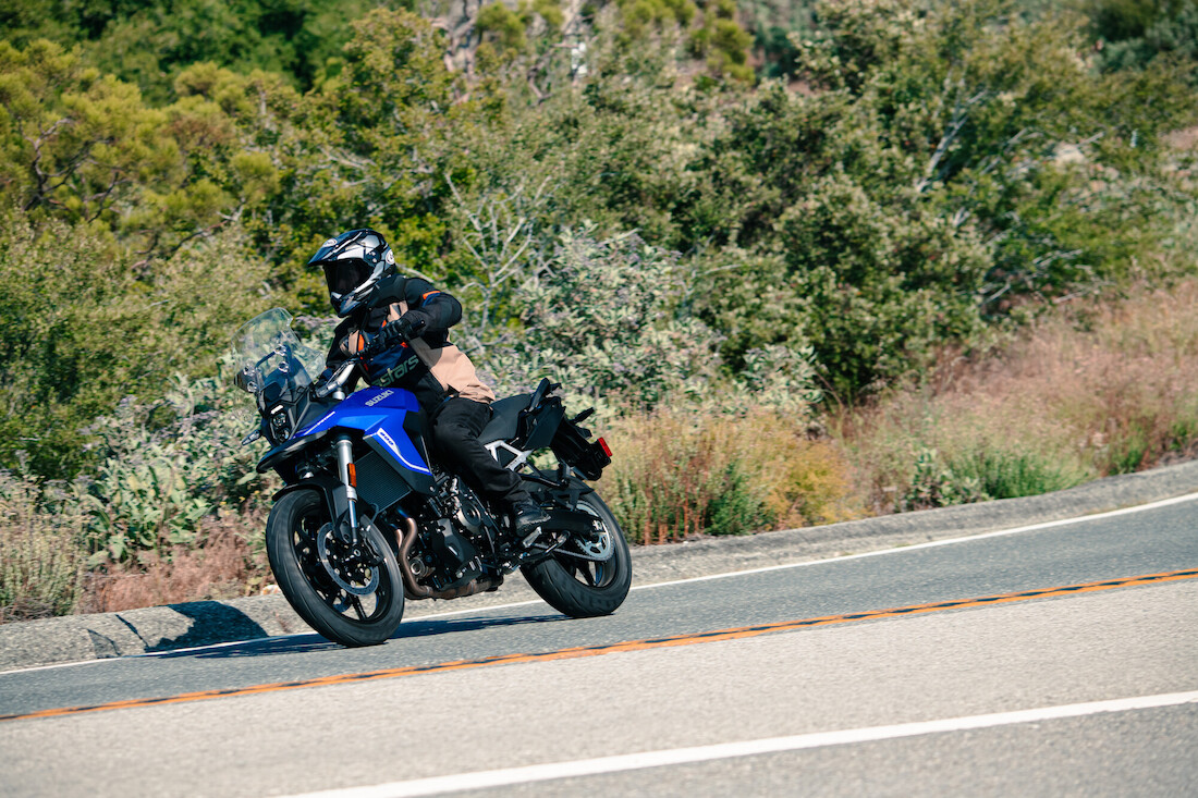 A rider doing an aggressive lean on a blue Suzuki V-Strom 800