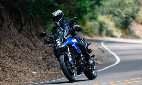 An Adventure rider on a twisty road riding a blue Suzuki V-Storm 800