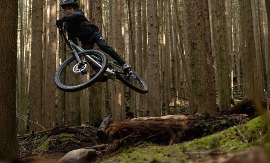 Mountain biker jumping in forest trail.