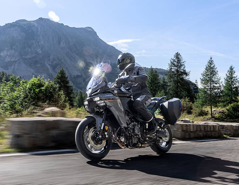 Motorcyclist on scenic mountain road in sunny weather.