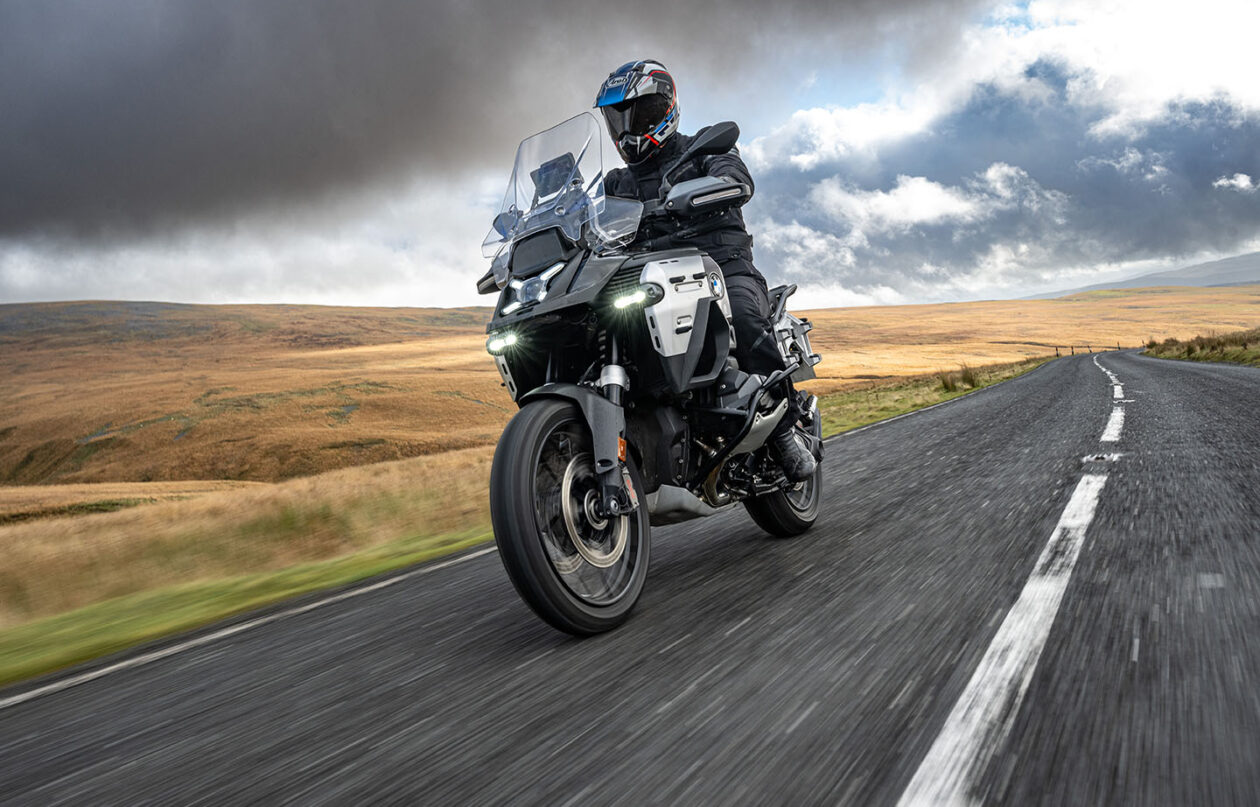 Motorcyclist riding through scenic countryside road.