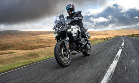 Motorcyclist riding through scenic countryside road.