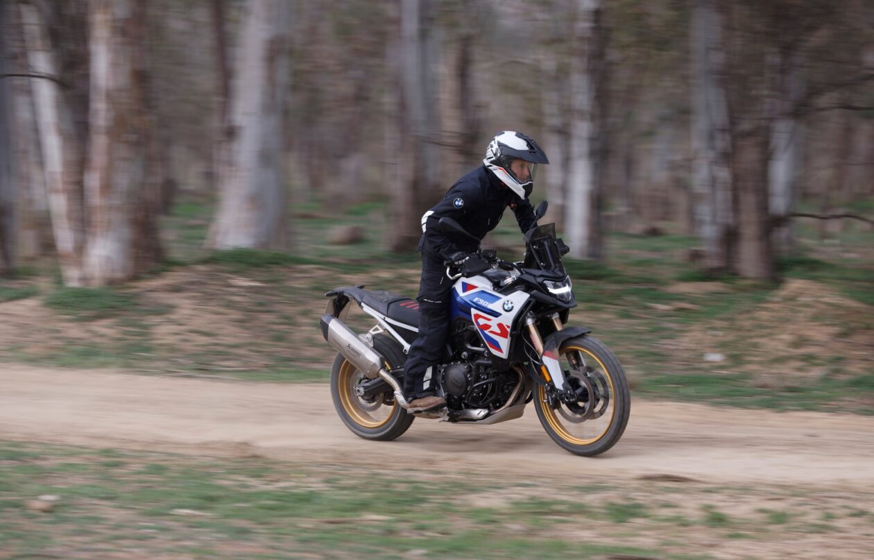 Motorcyclist riding through forest trail at speed.
