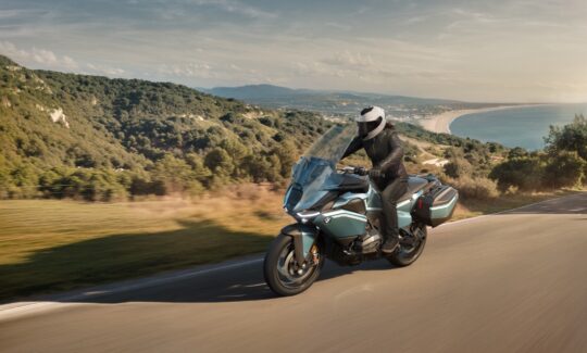 Motorcyclist rides on scenic coastal highway.