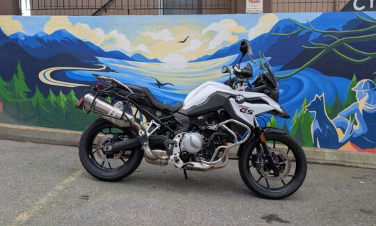 Motorcycle parked by scenic mural of mountains.