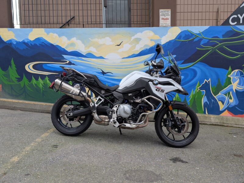 Motorcycle parked by scenic mural of mountains.
