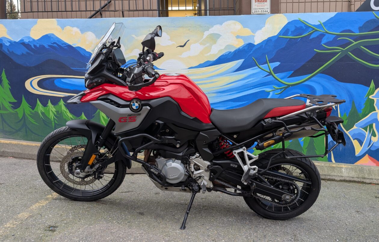 Red motorcycle parked in front of mural.