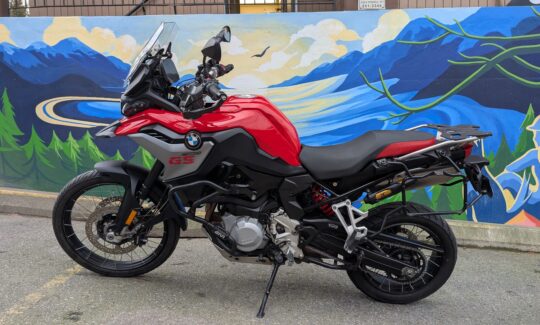 Red motorcycle parked in front of mural.