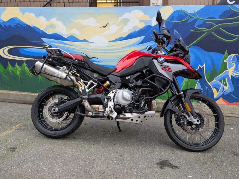 Red motorcycle parked in front of scenic mural.