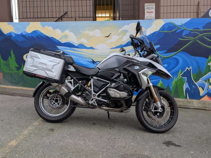 Motorcycle parked by colourful mural wall.