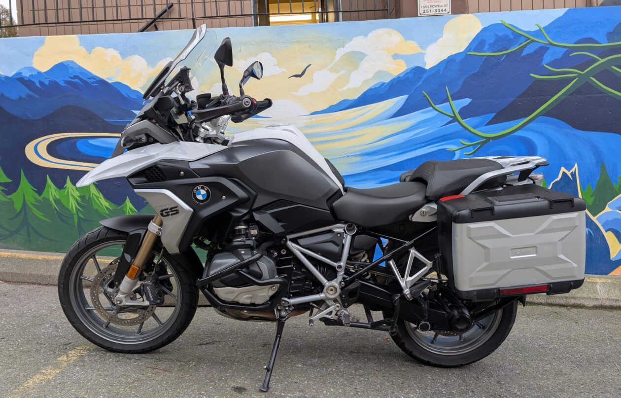 Motorcycle parked by a colourful mountain mural.