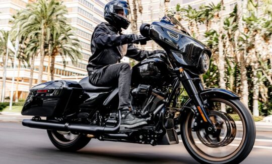 Person riding black motorcycle in urban setting.