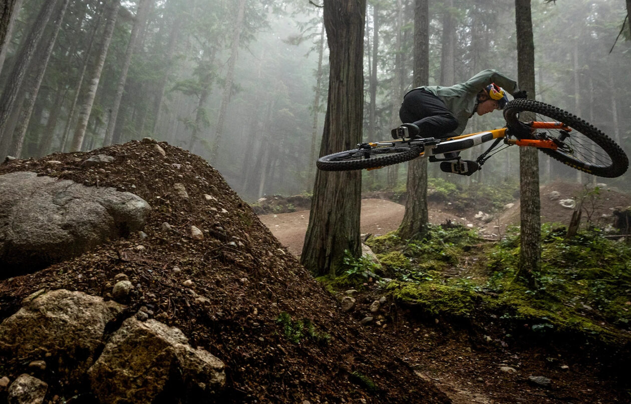 Mountain biker mid-air on forest trail jump